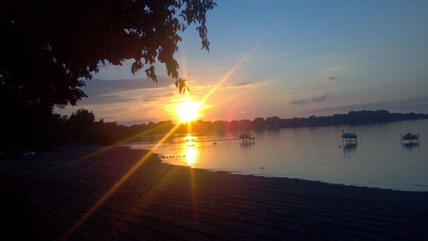A sunset over a calm lake with boats and a dock. - Waterfront 2 b.r. Bay View Cottage/sunsets/wineries/lighthouses/beaches/fishing (Sturgeon Bay)