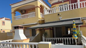 A multi-story building with a yellow facade, white balconies, and a gated entrance. - Air-conditioned 2 bedroom villa in Orihuela Costa with pool and sea 1 km (Orihuela Costa)