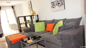 A modern living room with a grey sofa, a glass coffee table, and a green rug. - Air-conditioned 2 bedroom villa in Orihuela Costa with pool and sea 1 km (Orihuela Costa)