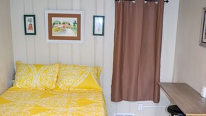 A bedroom with a bed, a desk, two chairs, and a window with curtains.