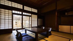 Una habitación japonesa tradicional con suelo de tatami, una mesa baja y puertas correderas.