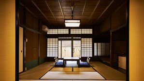 Una habitación japonesa tradicional con suelo de tatami, una mesa baja y puertas correderas.