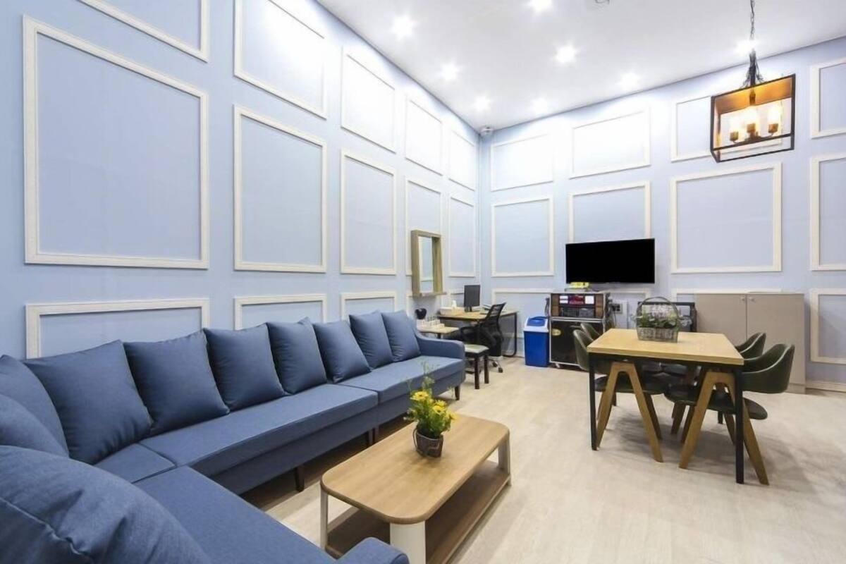 A modern living room with a blue sofa, a wooden coffee table, and a dining area with a table and chairs.
