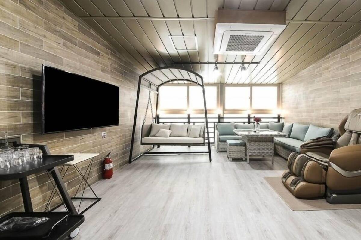 A modern living room with a TV, seating area, and massage chair.