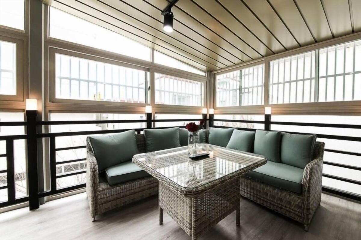 A sunlit room with wicker furniture, large windows, and a ceiling fan.