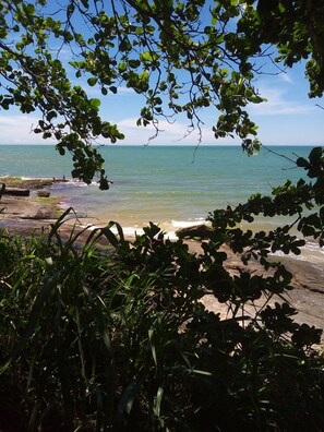 A coastal view with rocky shoreline, clear sky, and greenery framing the scene. - Beautiful house on Pau Grande beach, between Iriri and Piúma Min. 3 nights, max. 8 pax. (Lot. Portinho)
