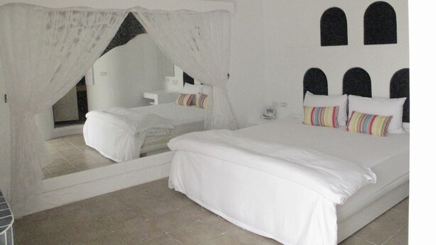 A bedroom with a large bed, a bedside table, a mirror, and a window. - Peanut House (Hengchun)