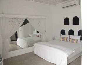A bedroom with a large bed, a bedside table, a mirror, and a window. - Peanut House (Hengchun)
