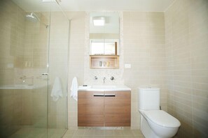 Un baño con cabina de ducha de vidrio, un lavabo con espejo y un inodoro.