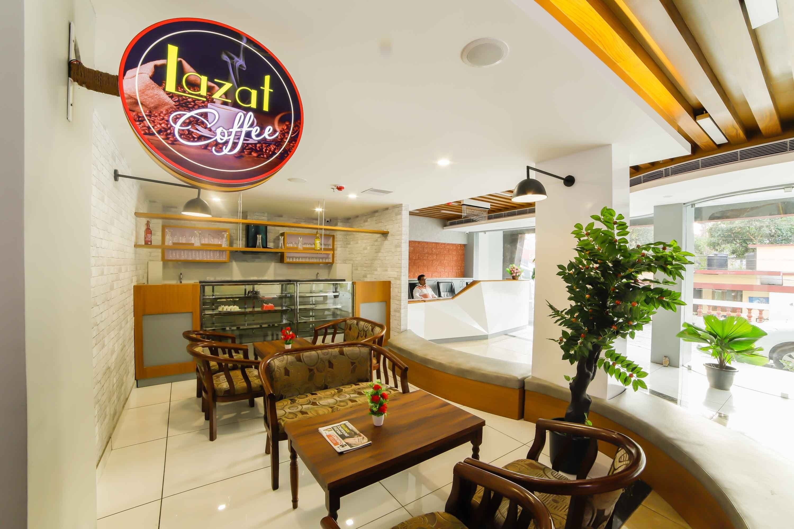 A cozy cafe interior with wooden furniture, a glass display case, and a large window offering a view of the street.