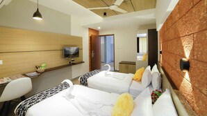 Una habitación de hotel con dos camas, un escritorio, una silla, un televisor y un ventilador de techo.