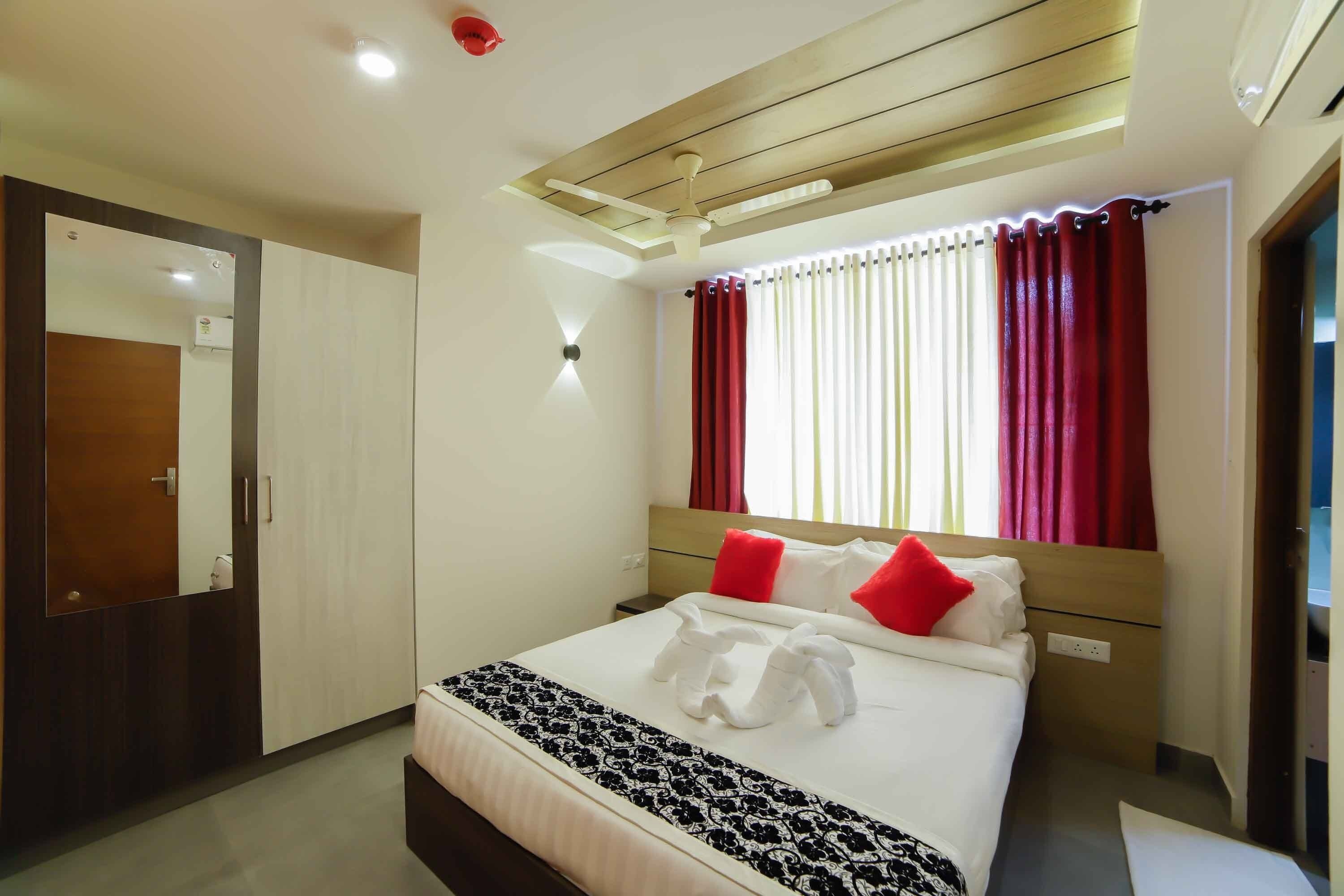 A hotel room with a bed, a wardrobe, a mirror, and a ceiling light.