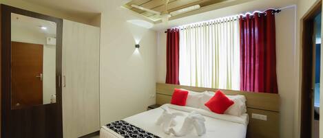 A hotel room with a bed, a wardrobe, a mirror, and a ceiling light.