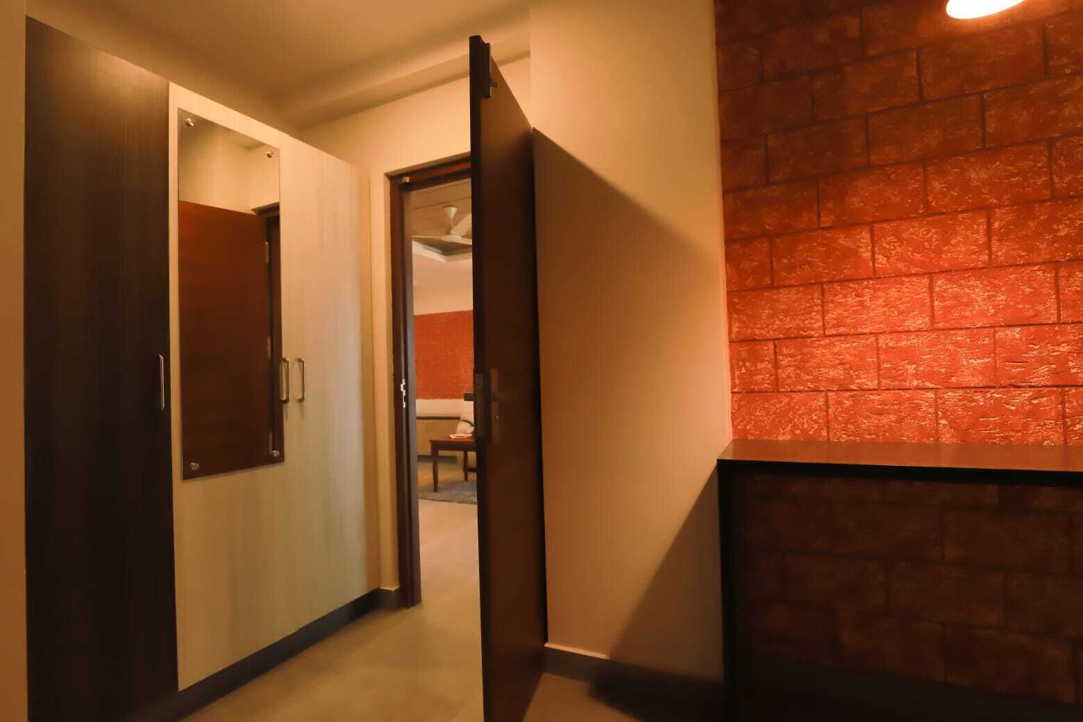 Un couloir avec une porte en bois, un mur en briques et un luminaire au plafond.