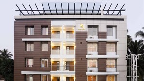 Un hotel de varios pisos con un diseño moderno, que cuenta con balcones, ventanas amplias y un techo plano.