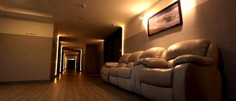 A hallway with a reclining sofa and a framed picture on the wall.