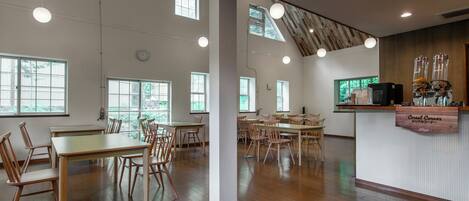 A spacious room with high ceilings, large windows, and a wooden reception desk.