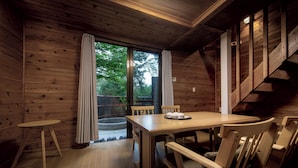 Un interior de madera con una mesa de comedor y sillas, una pequeña mesa redonda, y una escalera.