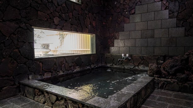 Un jacuzzi de paredes de piedra con ventana, escalones de piedra y una pared de piedra.