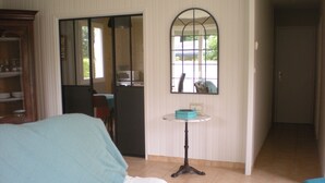 A hotel room with a bed, a small table with a blue tray, a mirror, and a view of the outside. - Gite Grandcamp Maisy. (Grandcamp-Maisy)
