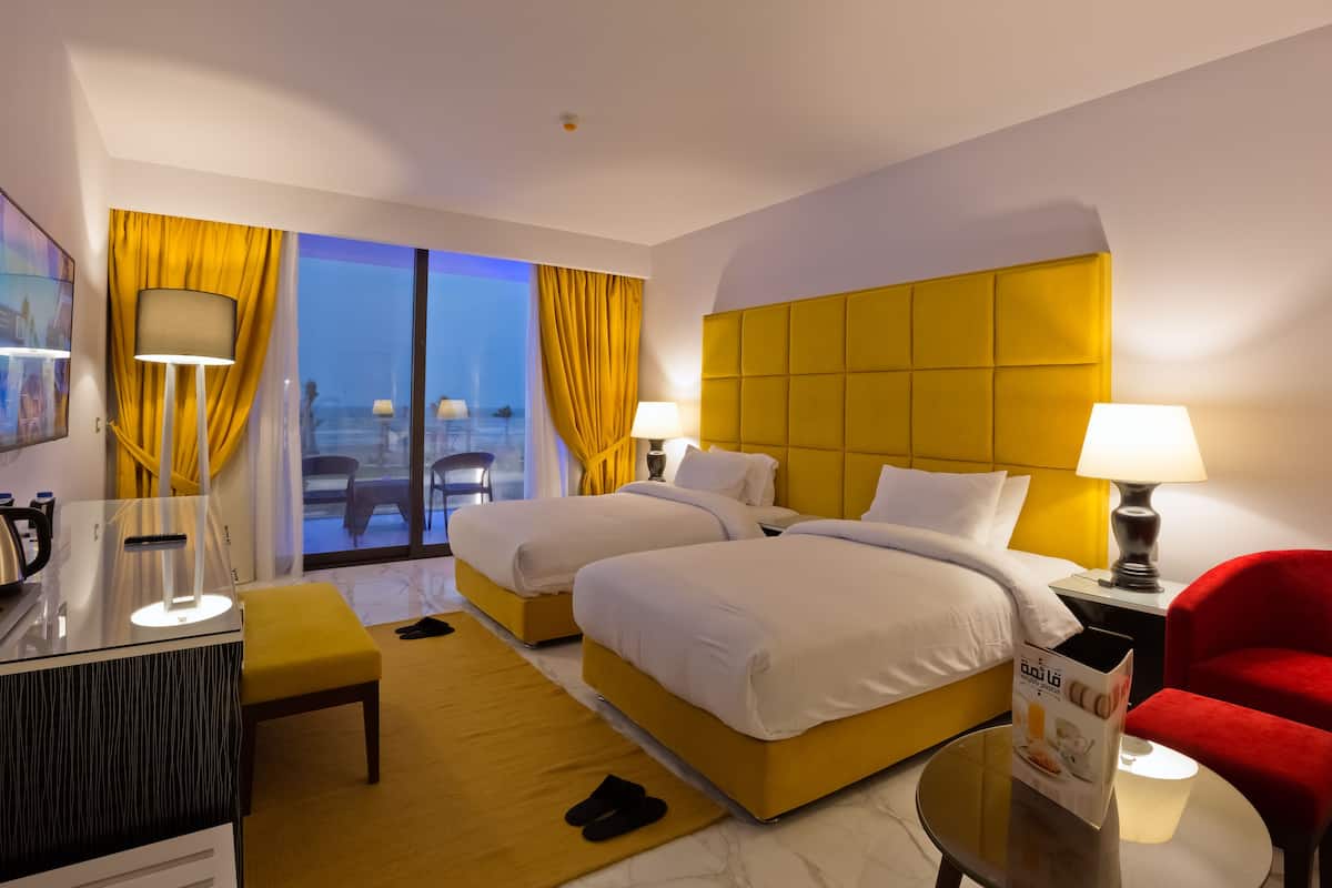Ett hotellrum med två sängar, ett skrivbord, en stol och utsikt över staden.