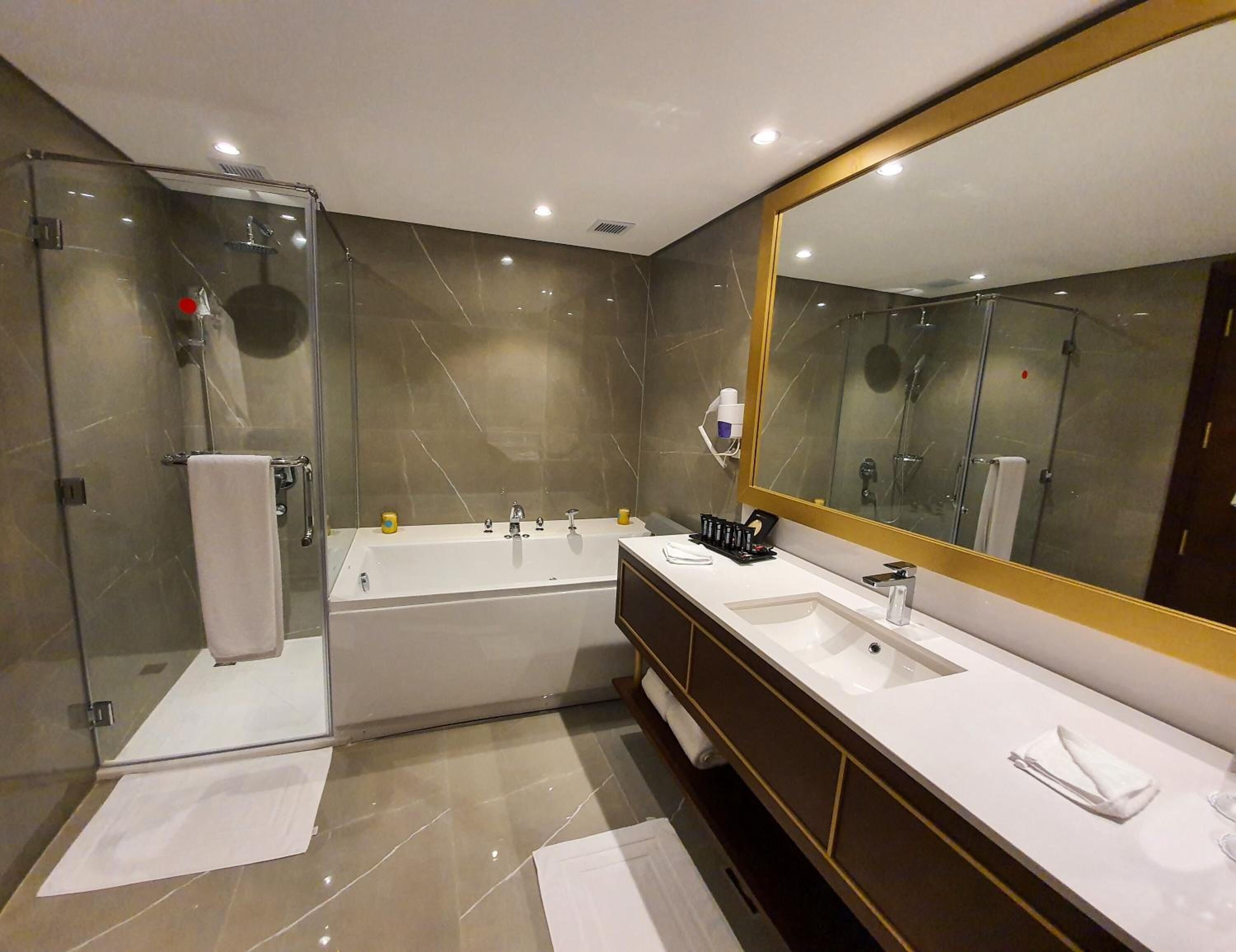 A modern bathroom with a glass-enclosed shower, a large bathtub, and a vanity with a mirror.