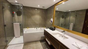 A modern bathroom with a glass-enclosed shower, a large bathtub, and a vanity with a mirror.