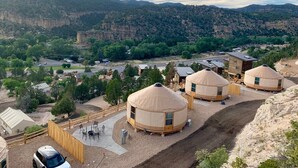 Un campement composé de trois yourtes, d’une terrasse en bois et offrant une vue sur le paysage environnant.