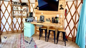 Une cuisine compacte équipée d’un four à micro-ondes, d’une machine à café et d’étagères en bois.