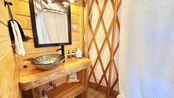 Un baño de madera con un espejo grande, un lavabo tipo cuenco y una cortina de ducha.