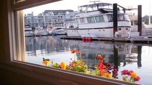 A marina with boats docked, a duck swimming in the water, and colorful flowers in the foreground.