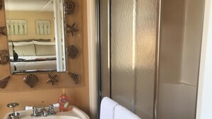 A bathroom with a sink, mirror, and shower.