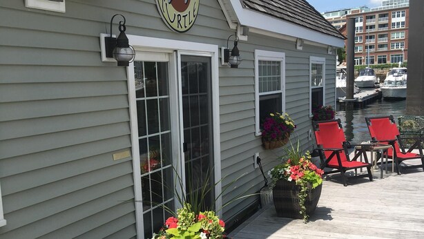 A building with a sign reading "GREEN TURTLE" and a dock with red chairs.