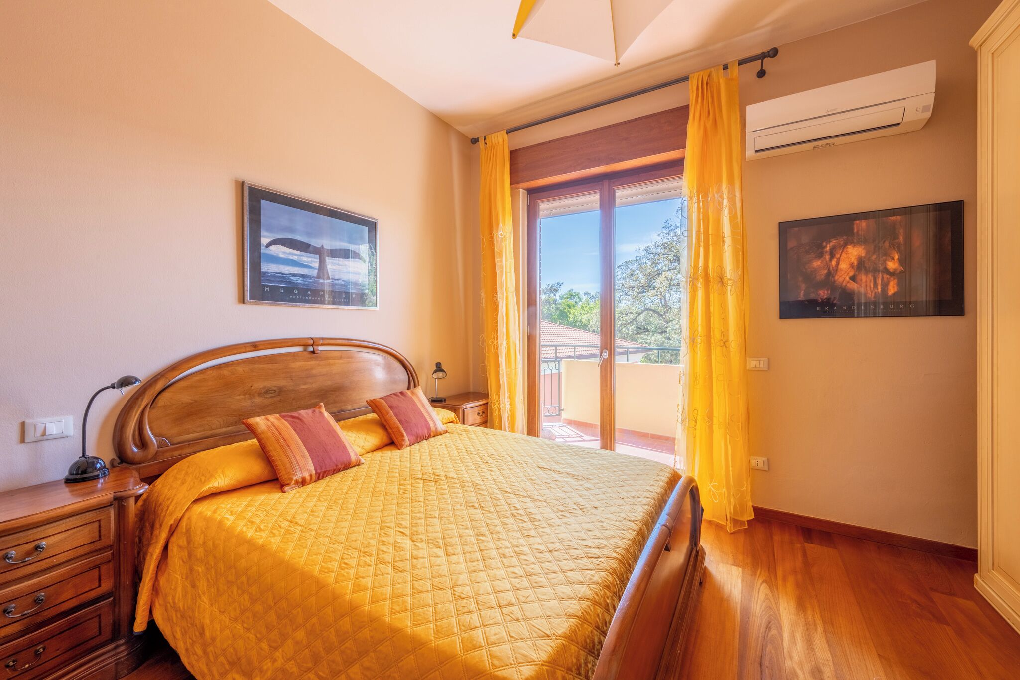 Une chambre avec un lit en bois, des rideaux jaunes et une vue sur l’extérieur.