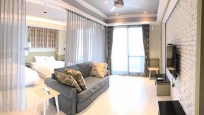 A modern hotel room with a bed, a sofa, a TV, and a minibar. - Jt158 B&B (Hengchun)