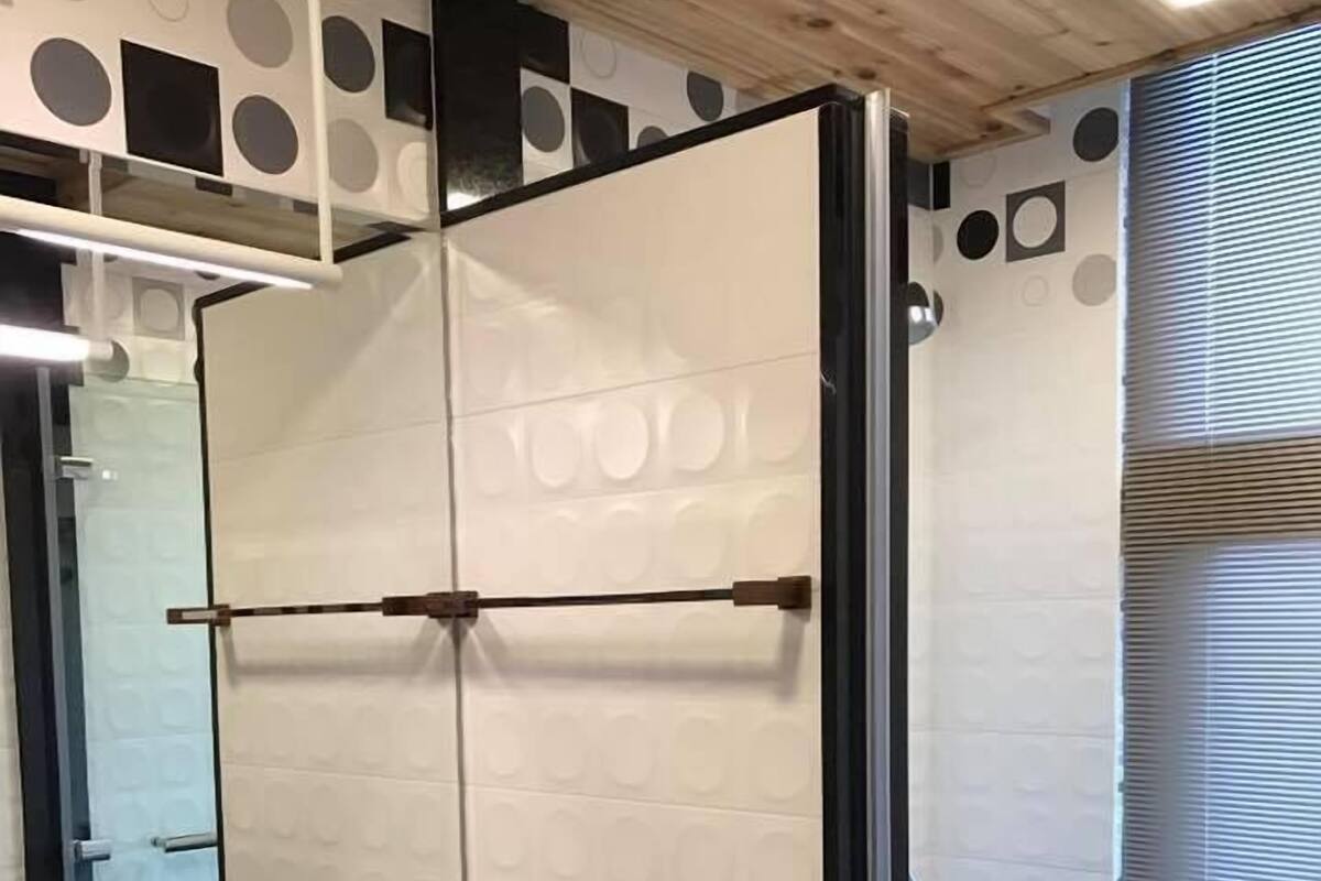 A bathroom with a wooden vanity, a large mirror, and a shower area with a glass door.