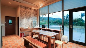 A spacious kitchen with a large island, a stone accent wall, and a view of the outdoors. - Jt158 B&B (Hengchun)