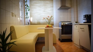 Una cucina compatta con un divano giallo, un tavolino con un cesto di frutta e un fornello.
