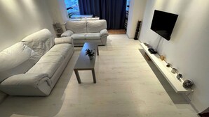 Un soggiorno moderno con un divano, un tavolino da caffè e una TV a parete.