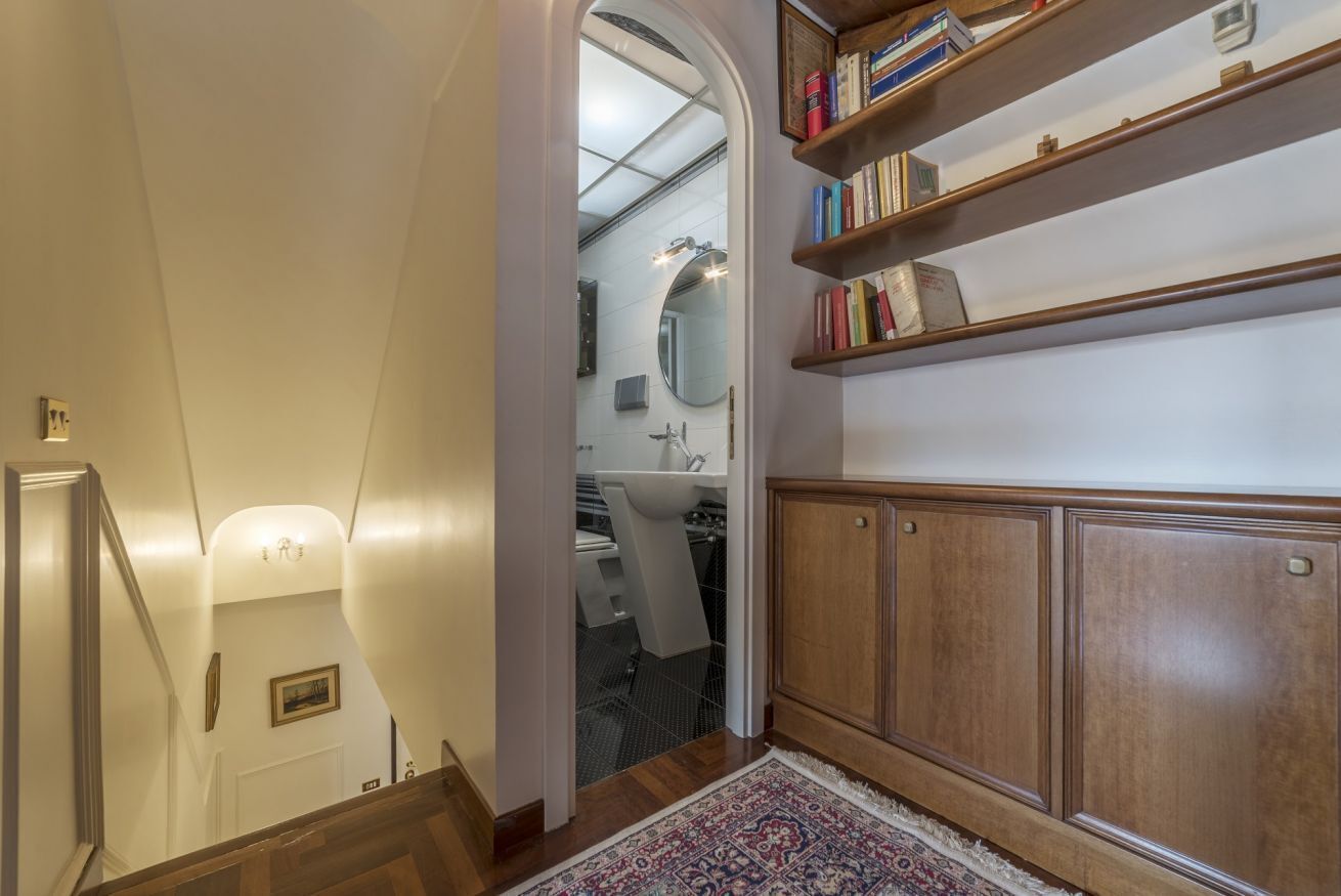 Un escalier menant à une salle de bain équipée d’un meuble en bois et d’une bibliothèque.