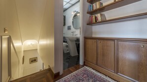 A staircase leading to a bathroom with a wooden cabinet and a bookshelf.