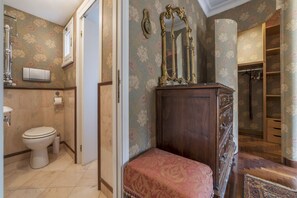A bathroom with a toilet, a sink, a mirror, and a wooden cabinet.