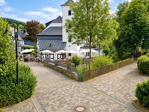 Un chemin pavé de pierres menant à un bâtiment doté d’une terrasse et de parasols.