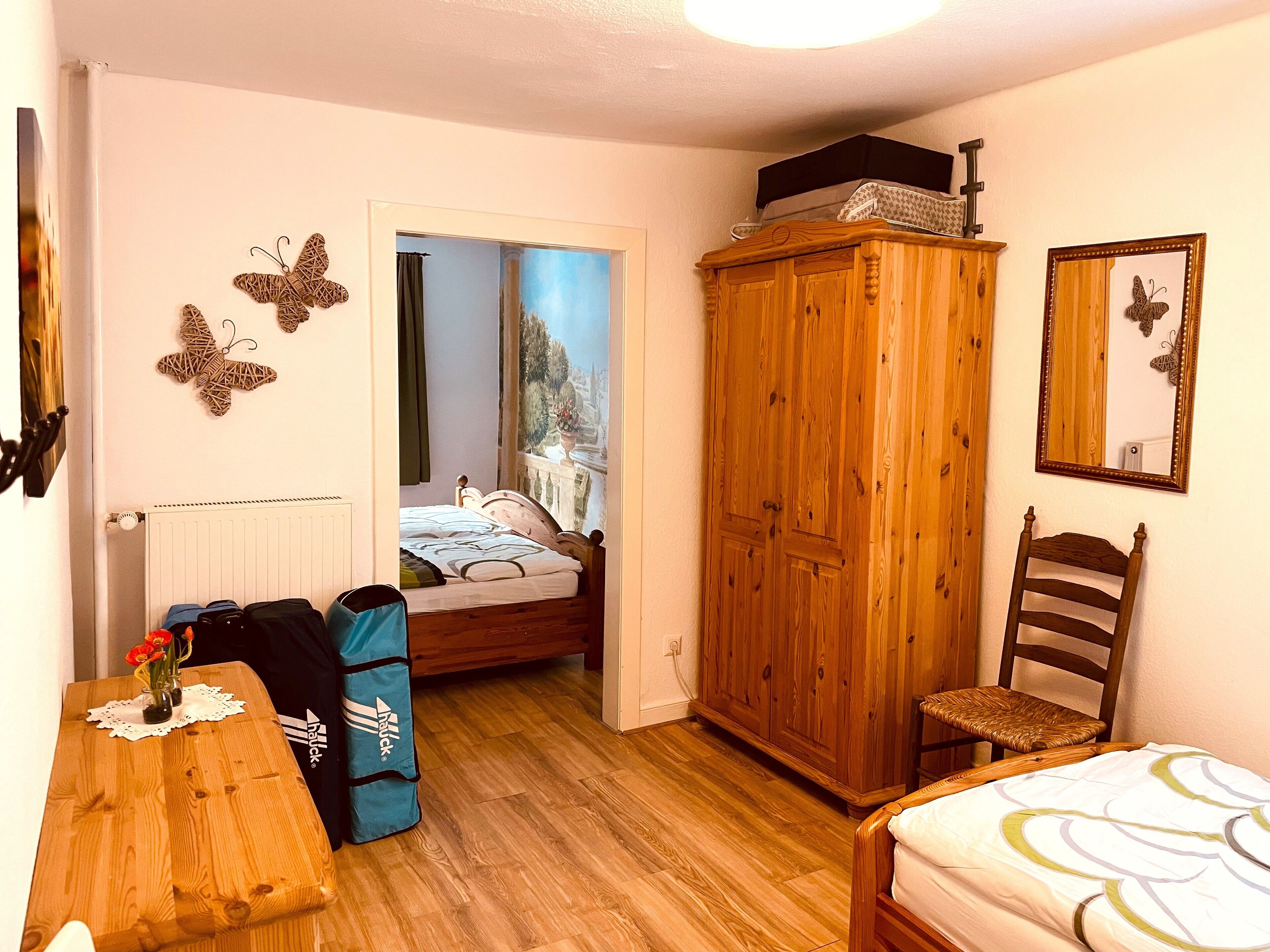 Un dormitorio con un armario de madera, una cama con vistas a la ciudad, una silla y una mesa con un bolso.