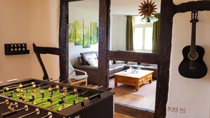 A living room with a foosball table, a sofa, a coffee table, and a guitar on the wall.