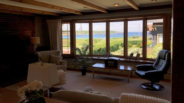 A living room with a large window offering a view of a body of water and greenery. There are two sofas, a coffee table, and a lamp. - ENDLESS VIEWS & Newly Updated!! (York)