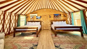 A yurt with two beds, wooden walls, a central skylight, and a patterned rug. - Glamping Yurt near Zion with Sunset Views (Orderville)