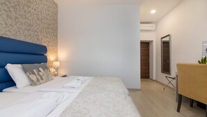 Habitación de hotel con cama, mesita de noche, lámpara y espejo.