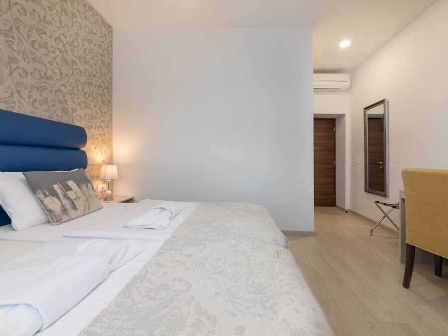 Habitación de hotel con cama, mesita de noche, lámpara y espejo.