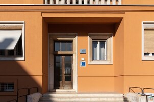 L'ingresso di un edificio con una porta doppia, due finestre e un piccolo cartello sopra la porta.